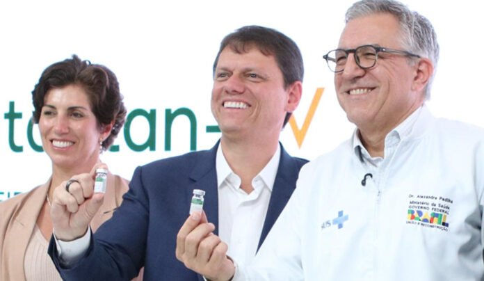 scientists at Brazil’s Butantan Institute holding a vial of the newly approved single-dose dengue vaccine.
