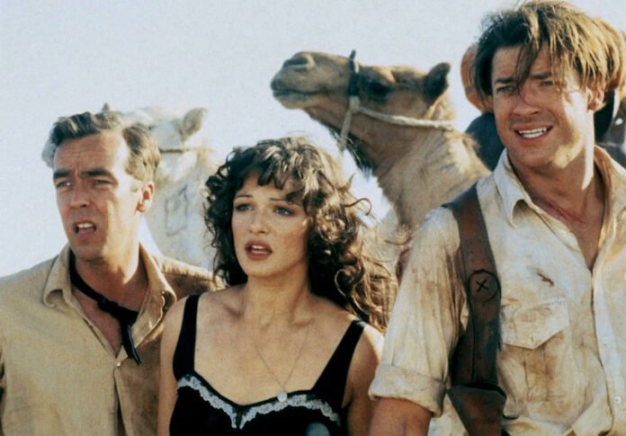 “Brendan Fraser and Rachel Weisz standing amid ancient Egyptian ruins with the iconic mummy symbol glowing behind them — poster for The Mummy Reboot 2026.”