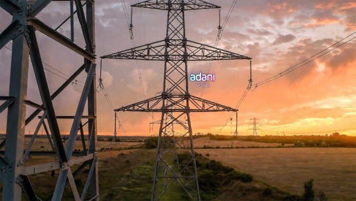 adani-energy-solutions-q3-f High-voltage electricity transmission tower in Indian countryside at sunset, illustrating power infrastructure growth for Adani Energy Solutions
