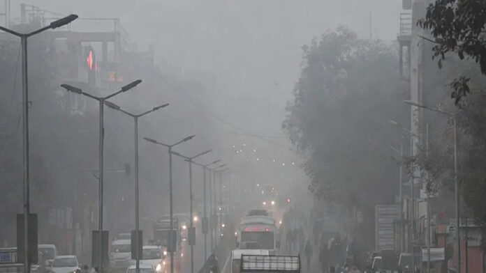 Smog-covered Delhi highway with trucks halted following non-essential entry ban due to severe air pollution.