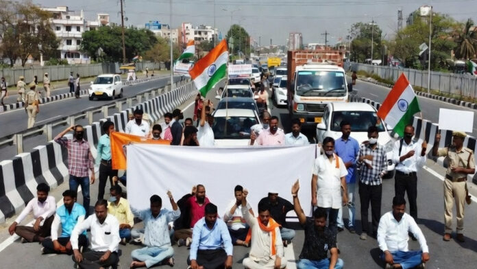 Protesters holding banners during Bharat Bandh demonstration with blocked highway in India