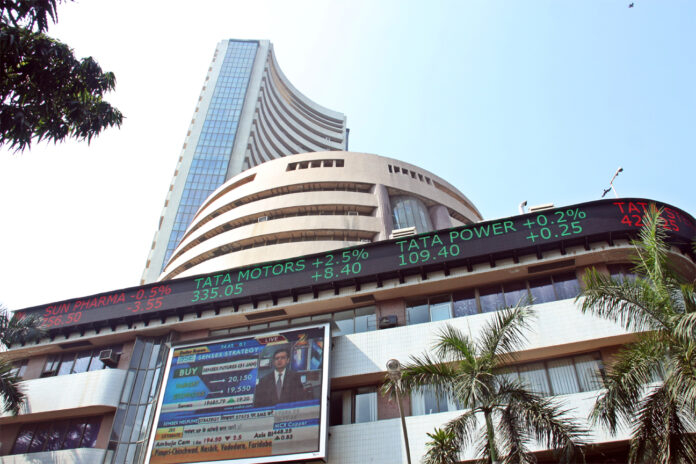 Bombay Stock Exchange building with green stock market numbers showing Sensex and Nifty gains