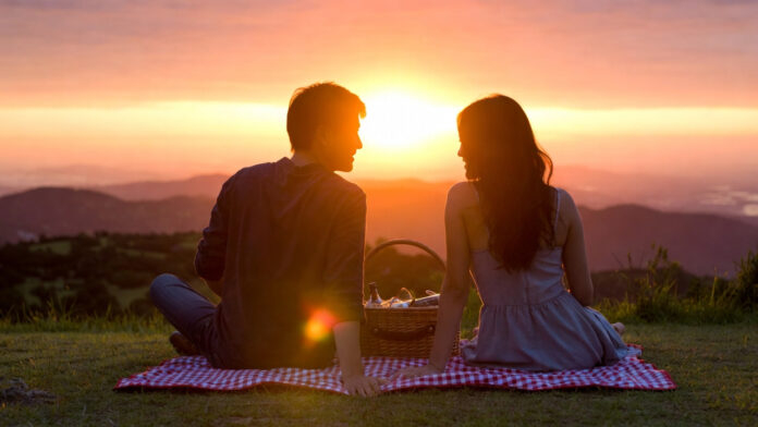 Couple enjoying romantic sunset picnic on Valentine’s Day