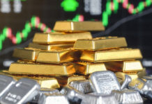 Gold Jumps Over ₹8,000, Silver Surges ₹23,000 Amid Iran Conflict Fears; Safe-Haven Buying Intensifies A close-up of gold bars and stacked silver bullion with a digital trading screen in the background showing rising price charts, symbolizing the sharp rally in precious metals.