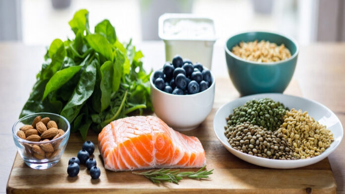 Top healthy foods for diabetes including leafy greens, salmon, berries, nuts, whole grains and yogurt arranged as a diabetes friendly diet meal
