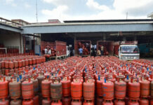 Govt Issues LPG Advisory Amid Global Tensions: Govt Urges Digital Booking, Says ‘No Fuel Shortage’ Despite Supply Concerns LPG gas cylinders stacked at distribution center in India with delivery staff preparing for supply