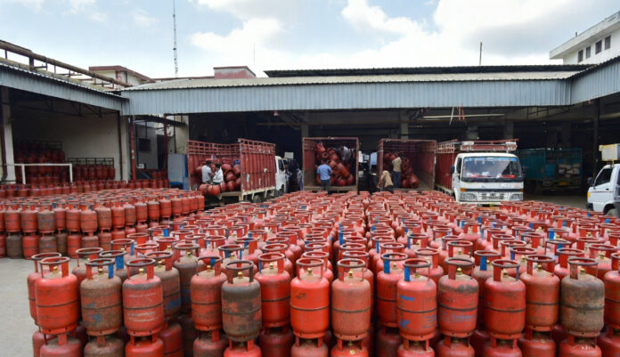 LPG gas cylinders stacked at distribution center in India with delivery staff preparing for supply