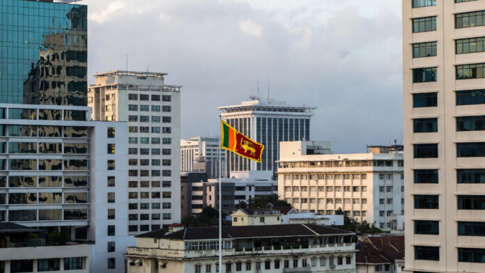 Colombo skyline with government buildings and Sri Lankan flag representing economic policy decision