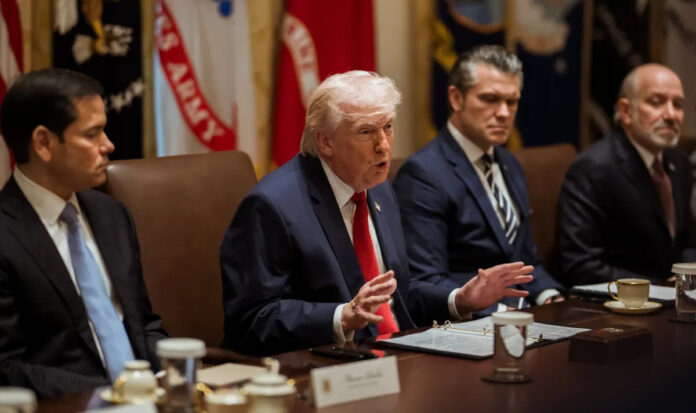 Donald Trump signing executive order on college sports reforms with documents and US flag